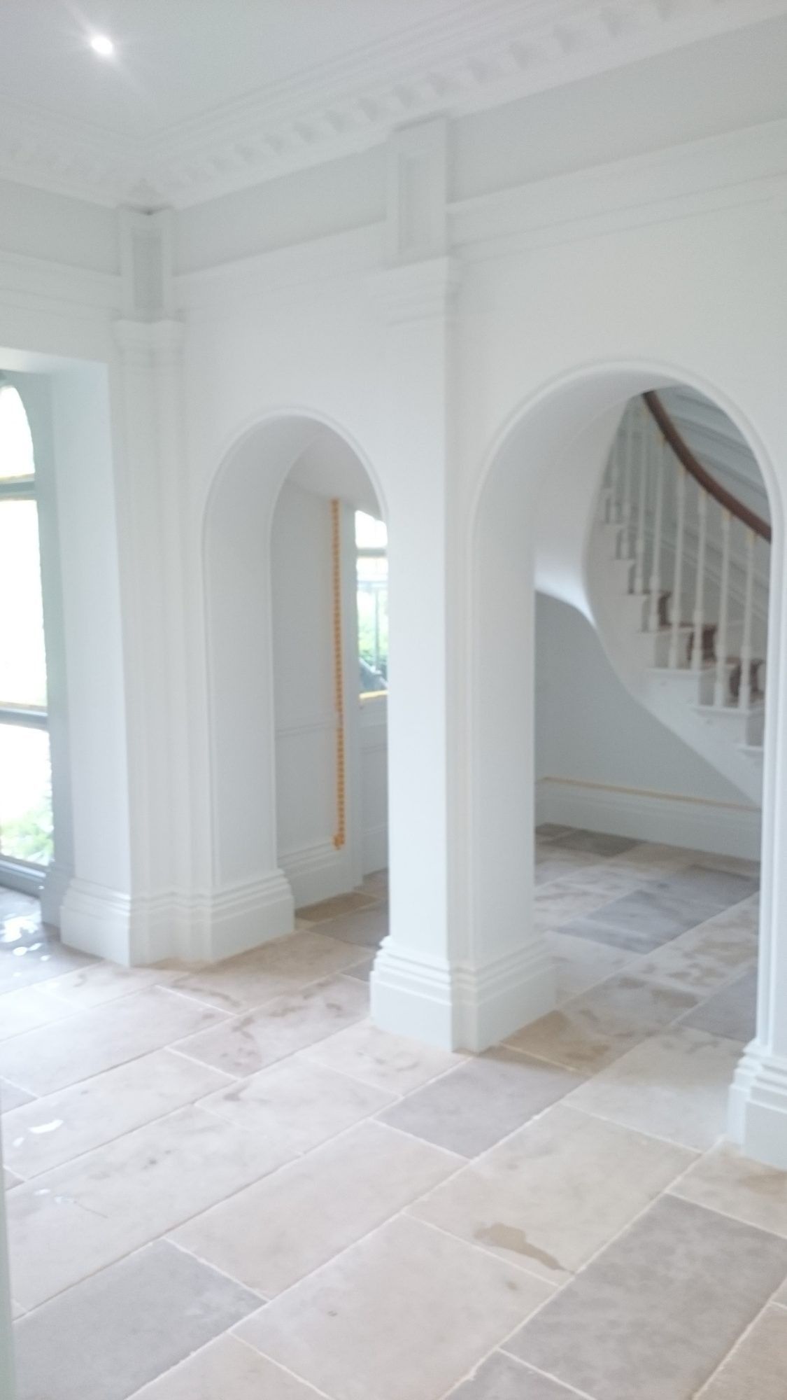Restored period hallway with arches, stone flags and a sweeping stair