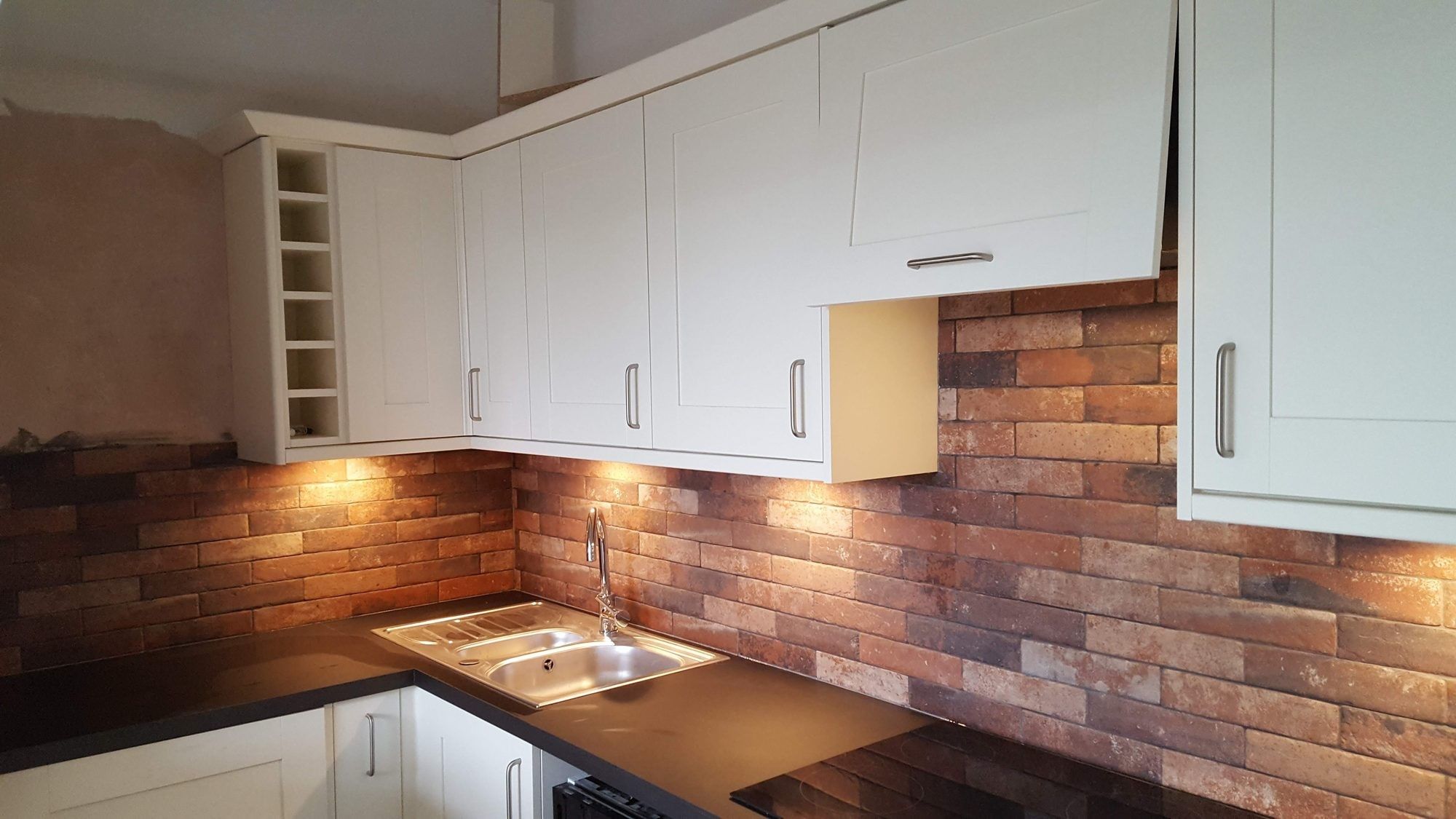 Shaker kitchen with brick-slip splashback and under-cabinet lighting